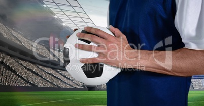 Midsection of soccer player holding ball on field