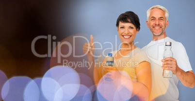 Happy man and woman with water bottles by bokeh