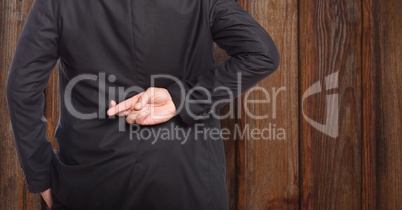 Midsection rear view of businessman crossing fingers against wood