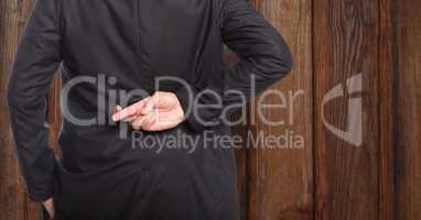 Midsection rear view of businessman crossing fingers against wood