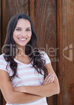 Portrait of happy female hipster standing arms crossed against wooden wall
