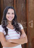 Portrait of happy female hipster standing arms crossed against wooden wall