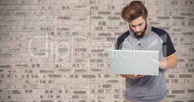 Hipster using laptop against wall