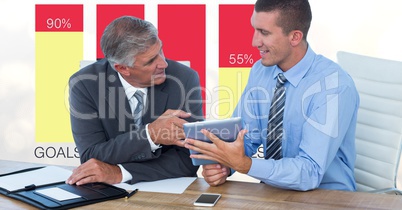 Businessmen with tablet PC discussing against graphs