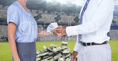Midsection of business people exchanging money at football stadium representing corruption