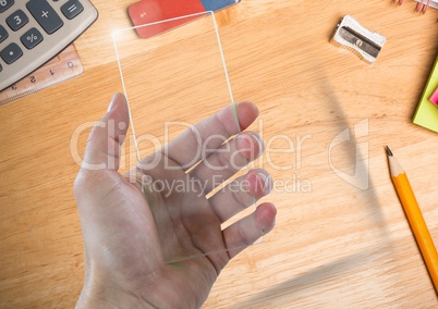 Hand with glass screen on table with objects