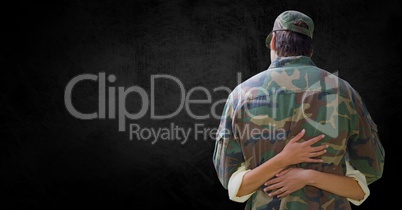 Back of soldier being hugged against black background