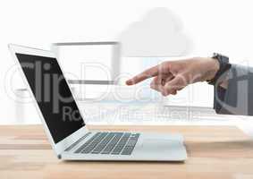 Hand pointing at laptop against blurry screens