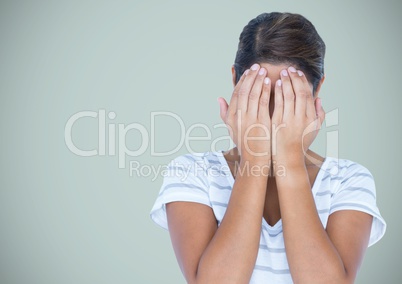 Woman with hands on face against light blue background
