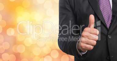 Midsection of businessman gesturing thumb up over bokeh