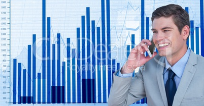 Smiling businessman using smart phone against graphs