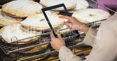Woman photographing food through tablet computer in grocery store