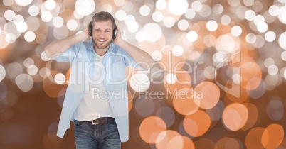 Smiling man listening to music on headphones against bokeh