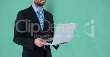 Midsection of businessman holding laptop over colored background