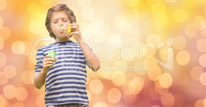 Boy playing with bubble wand over bokeh
