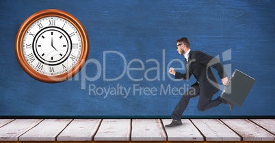 Businessman running with clock mounted on wall