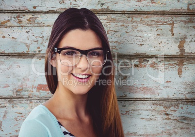 Portrait of happy woman wearing eyeglasses against wooden wall