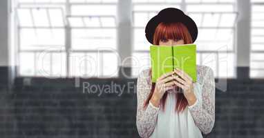 Female hipster covering face with book