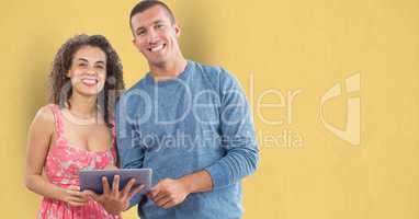 Portrait of happy business people with digital tablet against yellow background