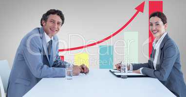Smiling business people at desk against graph