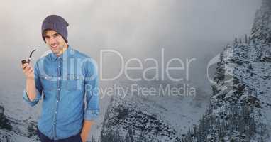 Smiling hipster holding smoking pipe against snowcapped mountain