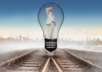 Businessman standing in light bulb over tracks