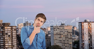 Thoughtful businessman with hand on chin against city