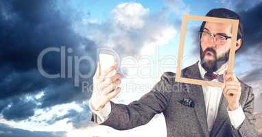 Hippie businessman holding frame while taking selfie on smart phone