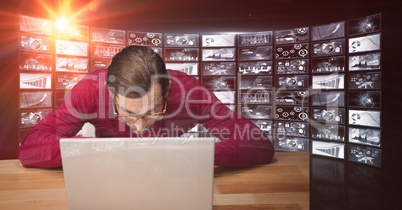 Male hacker using laptop against screens
