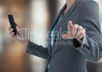Midsection of businesswoman holding smart phone while touching imaginary screen