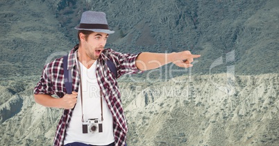 Excited traveler pointing while standing on mountain