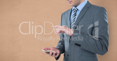 Midsection of businessman using smart phone against brown background
