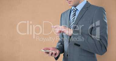 Midsection of businessman using smart phone against brown background