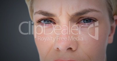 Close up of woman's angry eyes against grey background