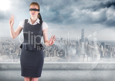 Business woman blindfolded against skyline with grey clouds and flare