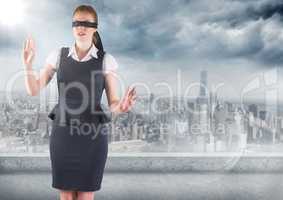 Business woman blindfolded against skyline with grey clouds and flare