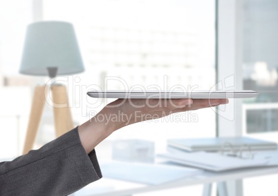 Hand holding tablet next to stylish room with lamp