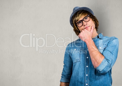 Thoughtful male hipster with hand on chin over gray background