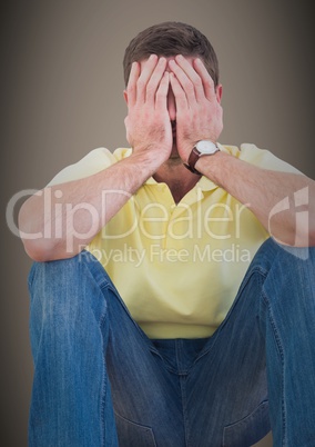 Man sitting with hands on face against brown background