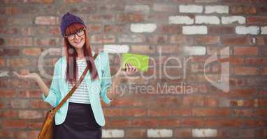 Happy female hipster holding clutch against brick wall