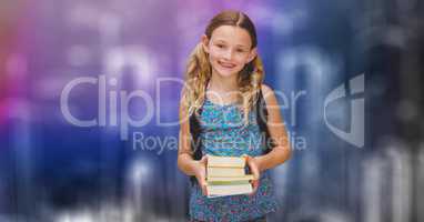 Happy schoolgirl holding books over blur background