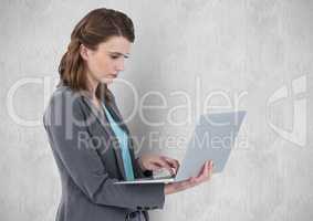 Businesswoman using laptop against wall