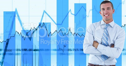 Smiling businessman with arms crossed against graphs