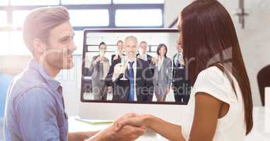 Business people shaking hands while having video conference with colleagues holding champagne glasse