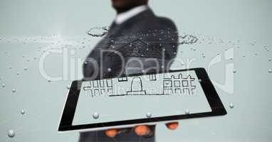 Midsection of businessman showing house on tablet PC's screen