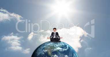 Businessman meditating on globe against sky