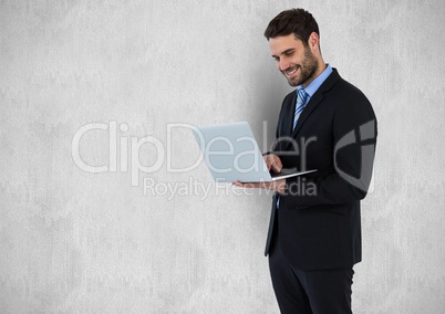Happy businessman using laptop against gray background
