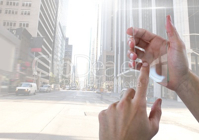 Hand touching glass screen in city with tall buildings