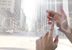 Hand touching glass screen in city with tall buildings