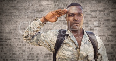 Soldier saluting against brown brick wall with grunge overlay